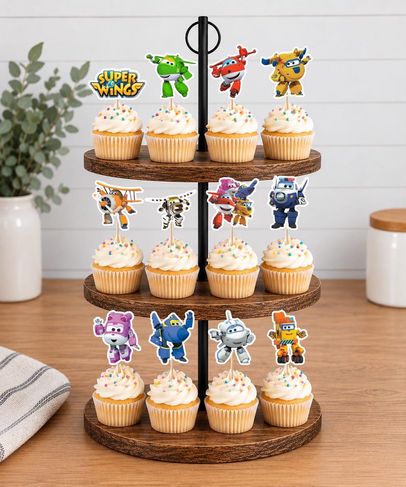 K&ouml;nnte beinhalten: Ein dreist&ouml;ckiger Cupcake-St&auml;nder aus Holz mit zw&ouml;lf Cupcakes, die mit wei&szlig;em Zuckerguss und bunten Streuseln verziert sind. Jeder Cupcake hat einen Super Wings-Figurenaufstecker aus Papier auf einem Holzspie&szlig;, darunter Jett, Donnie, Dizzy und Paul.