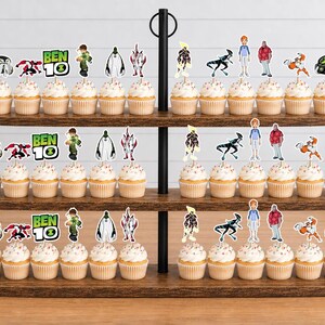 May include: A three-tiered wooden stand holding numerous cupcakes, each topped with a decorative paper cutout featuring various Ben 10 characters, the Ben 10 logo, and the Omnitrix symbol. The cupcakes are arranged in rows across the three oval shelves.