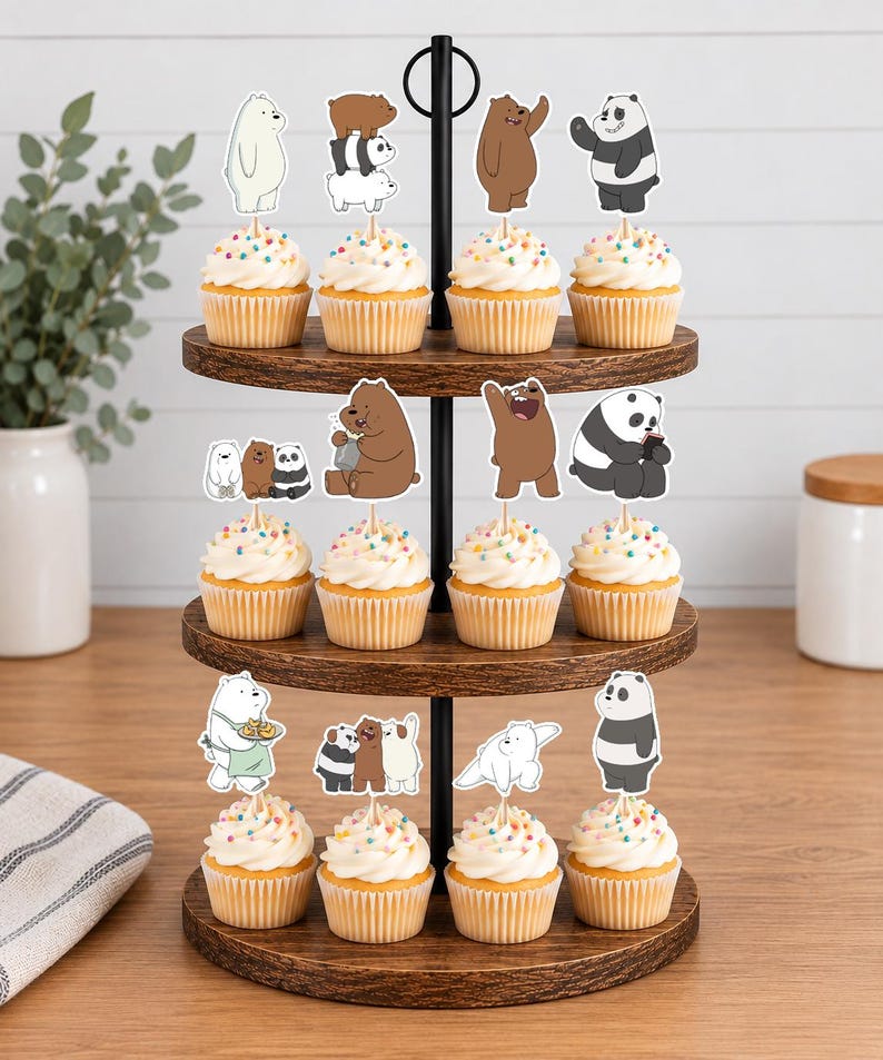 May include: A three-tiered wooden cupcake stand holding twelve cupcakes topped with white frosting and colourful sprinkles. Each cupcake features a paper topper depicting cartoon bears in various poses, including stacked bears and individual characters.