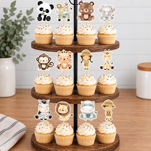 K&ouml;nnte beinhalten: Ein dreist&ouml;ckiger Holzst&auml;nder mit zw&ouml;lf Cupcakes, die mit dekorativen Papieraufstellern verschiedener Dschungeltiere verziert sind, darunter ein Panda, ein B&auml;r, ein Elefant, ein Affe, ein Tiger, eine Giraffe, ein Zebra, ein L&ouml;we, ein Flusspferd und zwei Safari-Entdecker.