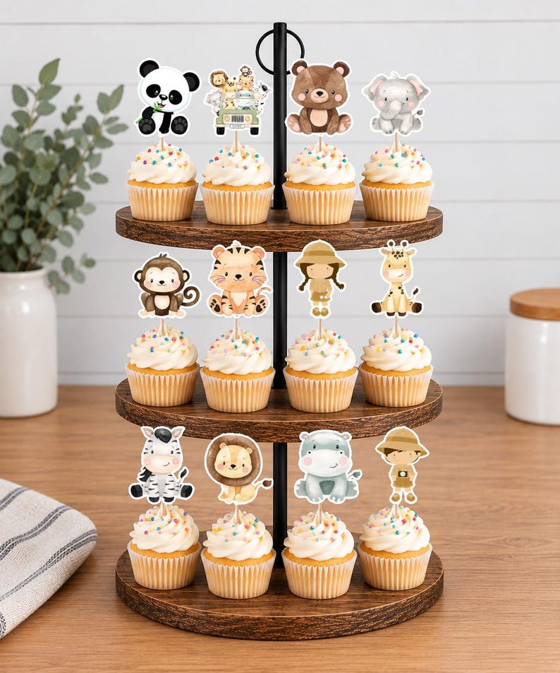 K&ouml;nnte beinhalten: Ein dreist&ouml;ckiger Holzst&auml;nder mit zw&ouml;lf Cupcakes, die mit dekorativen Papieraufstellern verschiedener Dschungeltiere verziert sind, darunter ein Panda, ein B&auml;r, ein Elefant, ein Affe, ein Tiger, eine Giraffe, ein Zebra, ein L&ouml;we, ein Flusspferd und zwei Safari-Entdecker.