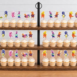 May include: A three-tiered wooden cupcake stand holding numerous cupcakes topped with colorful paper cutouts of cartoon characters from The Backyardigans, including Pablo, Tyrone, Uniqua, Tasha, and Austin, along with circular logo toppers.