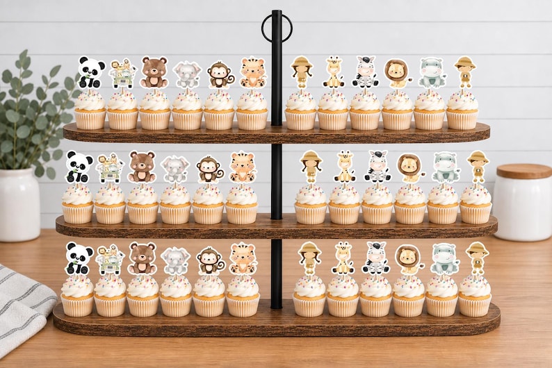 K&ouml;nnte beinhalten: Ein dreist&ouml;ckiger Cupcake-St&auml;nder aus Holz mit Reihen von Cupcakes, die mit Papieraufstellern von Safaritieren wie Pandas, B&auml;ren, Affen, Tigern, Giraffen, Zebras, L&ouml;wen und Entdeckern verziert sind, die in einem sich wiederholenden Muster angeordnet sind.