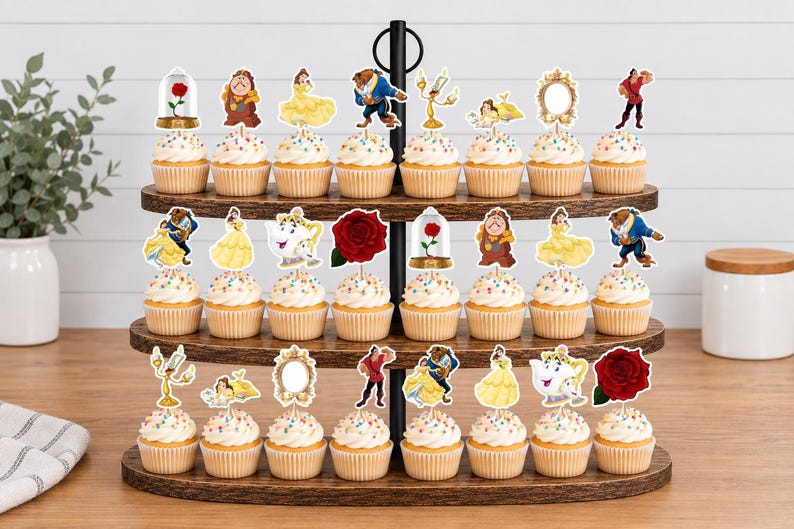 May include: A three-tiered wooden cupcake stand holding twenty-four cupcakes, each topped with a decorative paper cutout featuring characters and icons from Beauty and the Beast, including Belle, the Beast, Mrs. Potts, a red rose, and a mirror.