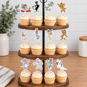 Peut inclure: Un pr&eacute;sentoir &agrave; cupcakes en bois &agrave; trois niveaux contenant douze cupcakes garnis de vermicelles color&eacute;s et de d&eacute;corations en papier Tom et Jerry. Les d&eacute;corations repr&eacute;sentent diverses poses de Tom, Jerry, Tuffy, Spike et d'autres personnages.