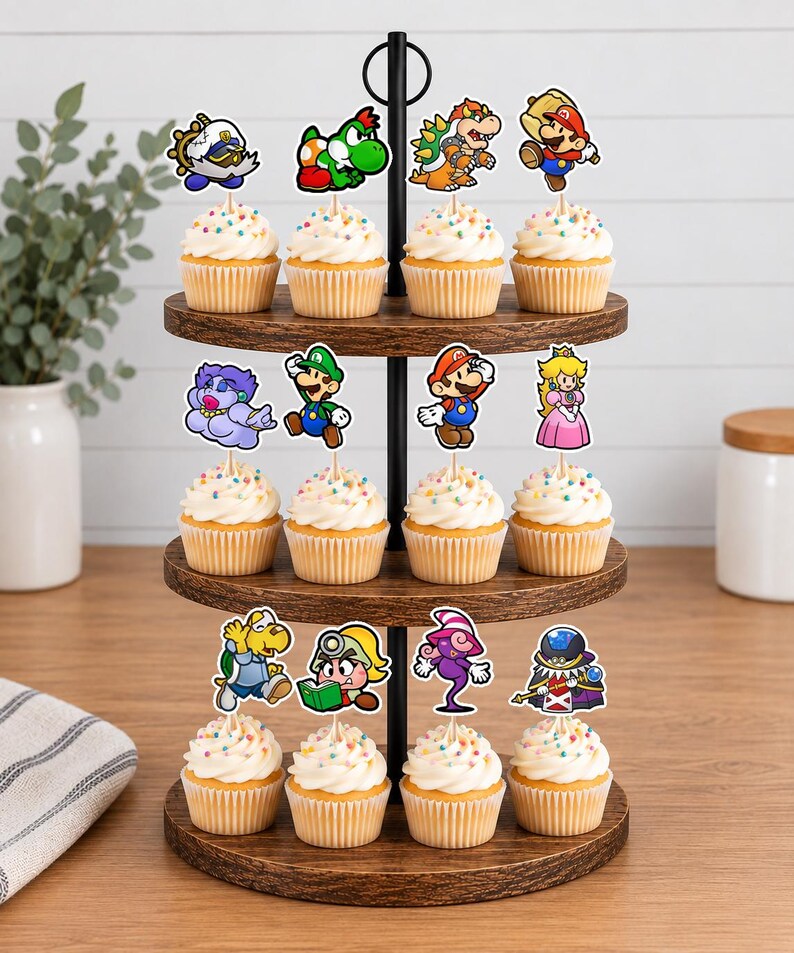 May include: A three-tiered wooden cupcake stand holding twelve cupcakes, each topped with a colorful paper cutout of a video game character. The characters include Mario, Luigi, Princess Peach, Bowser, Yoshi, and various other figures on wooden picks.