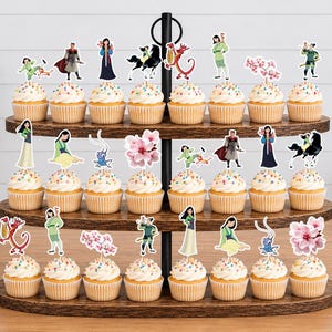 Peut inclure: Un pr&eacute;sentoir &agrave; cupcakes en bois &agrave; trois niveaux contenant vingt-quatre cupcakes, chacun surmont&eacute; d'une d&eacute;coupe en papier d&eacute;corative repr&eacute;sentant des personnages et des motifs de fleurs de cerisier du film Mulan, dont Mushu, Li Shang et Mulan.