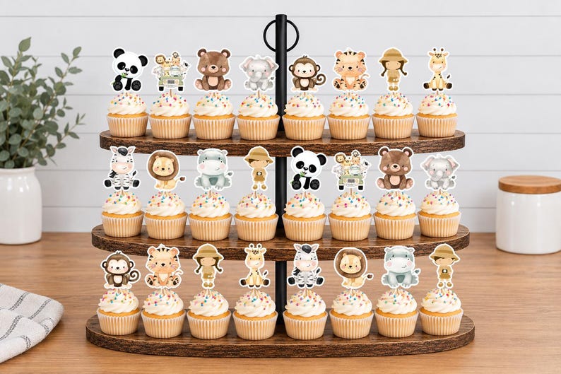 K&ouml;nnte beinhalten: Ein dreist&ouml;ckiger Cupcake-St&auml;nder aus Holz mit vierundzwanzig Cupcakes, die jeweils mit einem dekorativen Papieraufsteller mit Aquarellillustrationen von Dschungeltieren, Safari-Entdeckern und Fahrzeugen auf dem Zuckerguss verziert sind.