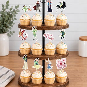 Peut inclure: Un pr&eacute;sentoir &agrave; cupcakes en bois &agrave; trois niveaux contenant douze cupcakes garnis de gla&ccedil;age blanc et de vermicelles color&eacute;s. Chaque cupcake est surmont&eacute; d'une d&eacute;coration en papier repr&eacute;sentant des personnages et des fleurs du film Mulan.