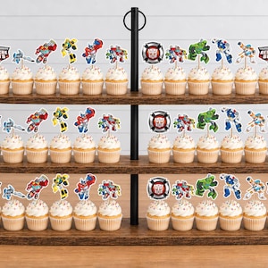 May include: A three-tiered wooden cupcake stand holding numerous cupcakes topped with Transformers Rescue Bots character paper toppers. Each cupcake features a decorative pick displaying various robot figures and the Transformers Rescue Bots logo.
