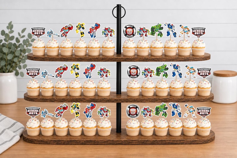 May include: A three-tiered wooden cupcake stand holding numerous cupcakes topped with Transformers Rescue Bots character paper toppers. Each cupcake features a decorative pick displaying various robot figures and the Transformers Rescue Bots logo.