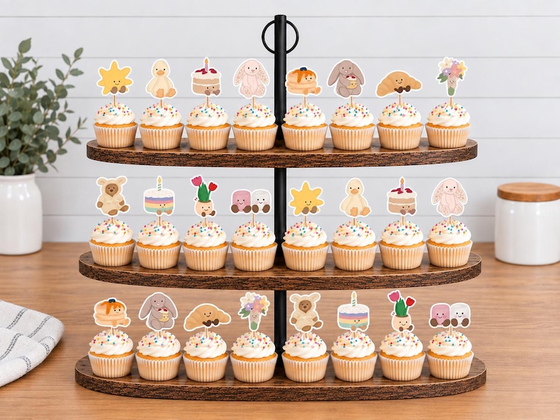 Puede incluir: Un soporte de tres niveles de madera oscura con veinticuatro cupcakes. Cada cupcake tiene una cobertura de glaseado blanco, chispas de colores y un recorte de papel con ilustraciones de dibujos animados de animales y flores.