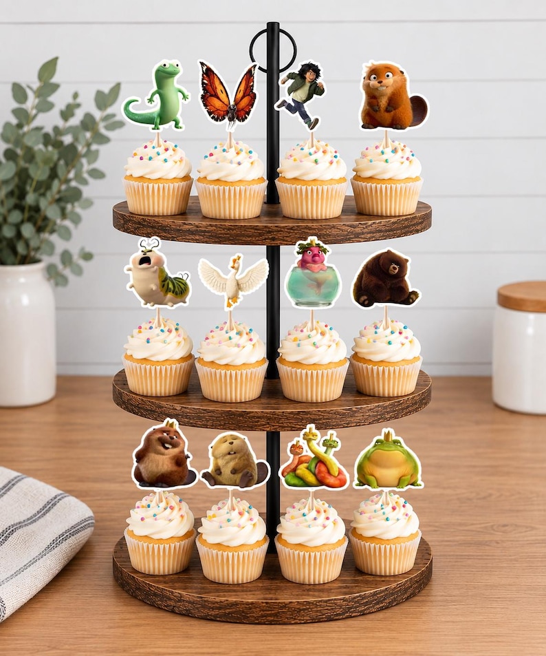 May include: A three-tiered wooden cupcake stand holding twelve cupcakes topped with white frosting and colorful sprinkles. Each cupcake features a decorative paper topper depicting various animated characters, including animals, a butterfly, and a person.