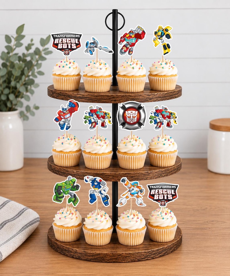 May include: A three-tiered wooden stand holding twelve cupcakes topped with white frosting and colorful sprinkles. Each cupcake features a paper topper depicting Transformers Rescue Bots characters, logos, and a silver Autobot emblem.