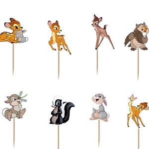 May include: A set of twelve decorative cupcake toppers featuring various cartoon forest animals including deer, a rabbit, a skunk, an owl, and a stag, each attached to a thin wooden pick for insertion into food items for themed party displays.