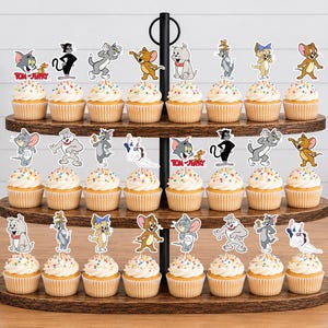 Peut inclure: Un pr&eacute;sentoir &agrave; cupcakes en bois &agrave; trois niveaux contenant vingt-quatre cupcakes, chacun surmont&eacute; d'une d&eacute;coupe en papier color&eacute;e repr&eacute;sentant les personnages de Tom et Jerry. Les personnages incluent Tom, Jerry, Spike et Tuffy dans diverses poses.