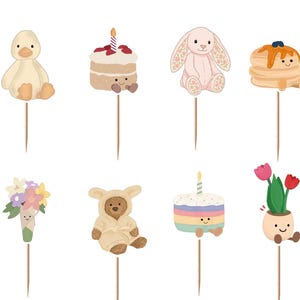 Puede incluir: Un conjunto de doce adornos decorativos para cupcakes con personajes ilustrados que incluyen un sol amarillo, un pato, un pastel, un conejo, tortitas, un oso, un cruas&aacute;n, un ramo de flores, un osito de peluche, un pastel arco&iacute;ris, tulipanes y nubes.