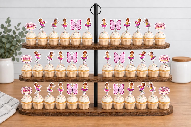 May include: A three-tiered wooden cupcake stand holding numerous cupcakes topped with decorative paper toppers. The toppers feature illustrations of a girl in a pink dress, pink butterflies, and signs with the text Fancy Nancy in pink script.