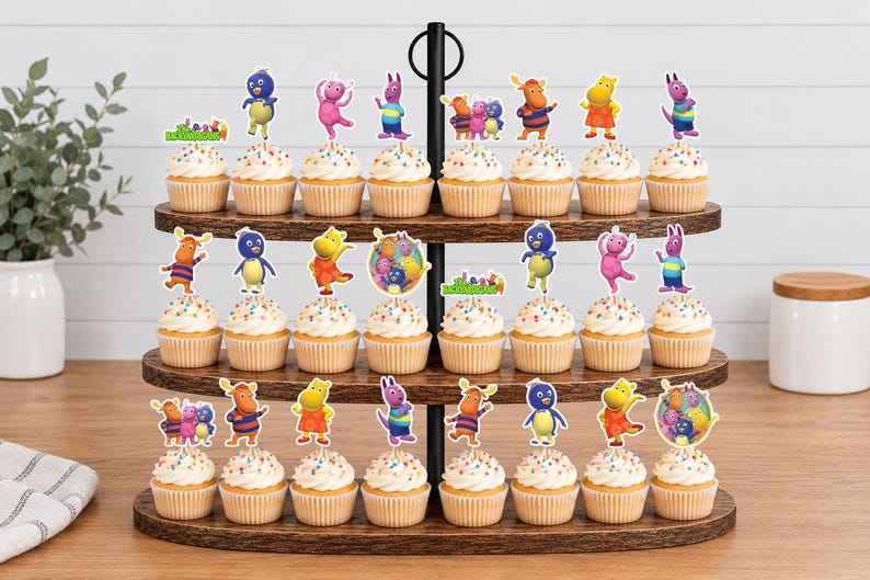 May include: A three-tiered wooden stand holding twenty-four cupcakes topped with colorful paper cutouts of cartoon characters from The Backyardigans. Each cupcake features a different character pose or group illustration on a small stick.