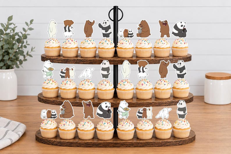 May include: A three-tiered wooden cupcake stand holding twenty-four cupcakes, each topped with a colourful sprinkle frosting and a paper cutout of characters from the animated series We Bare Bears, featuring Grizzly, Panda, and Ice Bear in various poses.