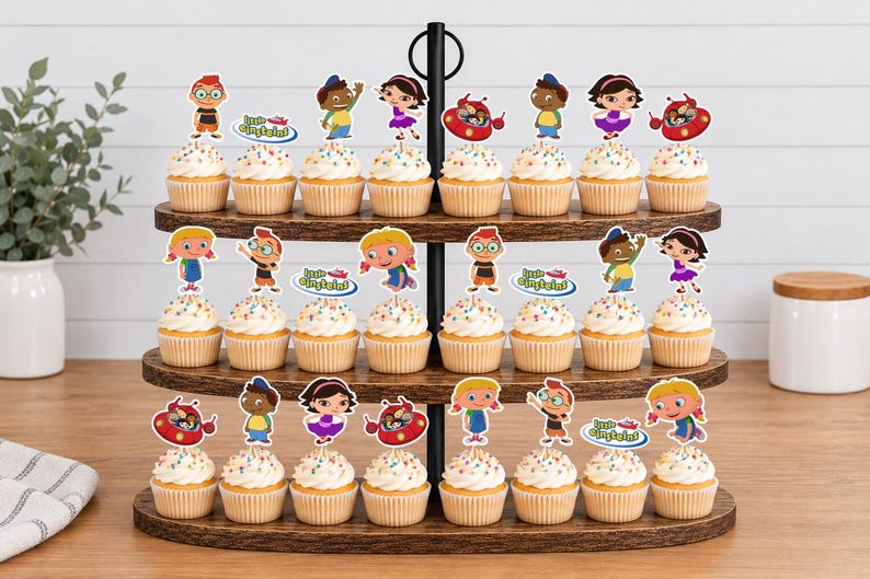 Puede incluir: Un soporte de madera para cupcakes de tres niveles con veinticuatro cupcakes decorados con adornos de papel de los Little Einsteins. Cada cupcake tiene un envoltorio de papel blanco y recortes coloridos de Leo, June, Quincy, Annie y Rocket.