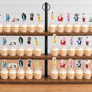 May include: A three-tiered wooden stand holding rows of cupcakes topped with paper cutouts of animated characters from the movie Sing. The characters include a koala, a pig, a gorilla, a porcupine, and others, each attached to a small wooden pick.