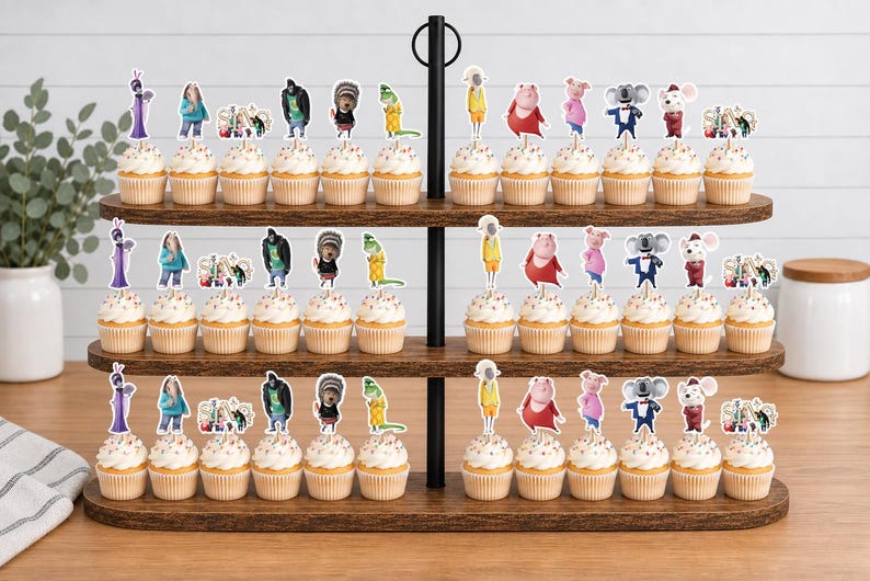 May include: A three-tiered wooden stand holding rows of cupcakes topped with paper cutouts of animated characters from the movie Sing. The characters include a koala, a pig, a gorilla, a porcupine, and others, each attached to a small wooden pick.
