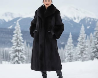 May include: A full-length black fur coat with a wide collar and long sleeves. The coat is worn with black boots. The background features snow-covered trees and mountains, creating a winter scene.