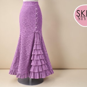 May include: A lilac-colored, floor-length skirt with a floral pattern. The skirt features a high waist, decorative bows, and a tiered ruffle detail on the side. The skirt is displayed on a mannequin. The logo "SKIRT STYLE" is visible.