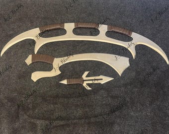 May include: A set of three silver-toned metal blades with brown wrapped handles. The top piece is a long, curved double-pointed blade with cutouts. The middle piece is a curved blade, and the bottom piece is a small, pointed dagger-like blade.