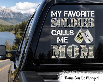 May include: A square vinyl decal for a vehicle window featuring the text MY FAVORITE SOLDIER CALLS ME MOM in a camouflage pattern. Two silver-toned military dog tags are attached to the text, one with the U.S. Army logo and one with the name WILLIAM.