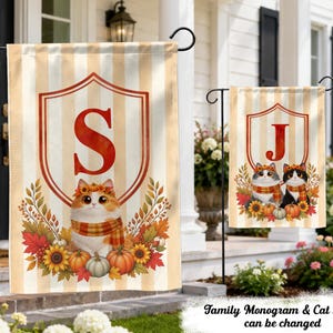 May include: Two vertical garden flags featuring a beige and white striped background. The larger flag displays a red shield with the letter S and a ginger cat wearing a scarf and floral crown. The smaller flag shows a red shield with the letter J and two cats.