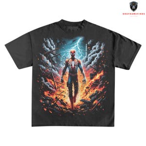 May include: Black t-shirt featuring a vibrant graphic of Spider-Man in a dynamic pose amidst a fiery, war-torn environment. The design includes lightning and debris, creating a dramatic superhero theme.
