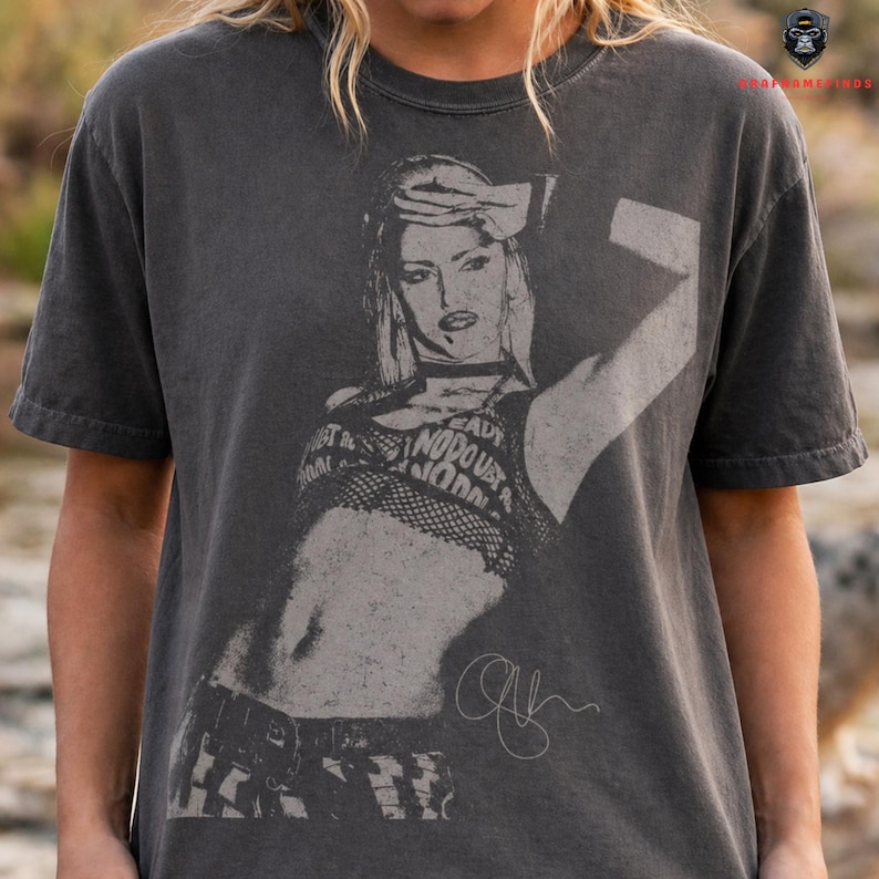 Peut inclure: T-shirt gris fonc&eacute; avec un motif noir et blanc d'une femme et le texte "READY, NO DOUBT, NO DRAMA". Le t-shirt a un aspect vintage et vieilli.