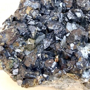 May include: A mineral specimen featuring a cluster of dark, metallic, cubic crystals intermixed with translucent, colorless, prismatic quartz points and small patches of brassy, reflective pyrite embedded within the rocky matrix.