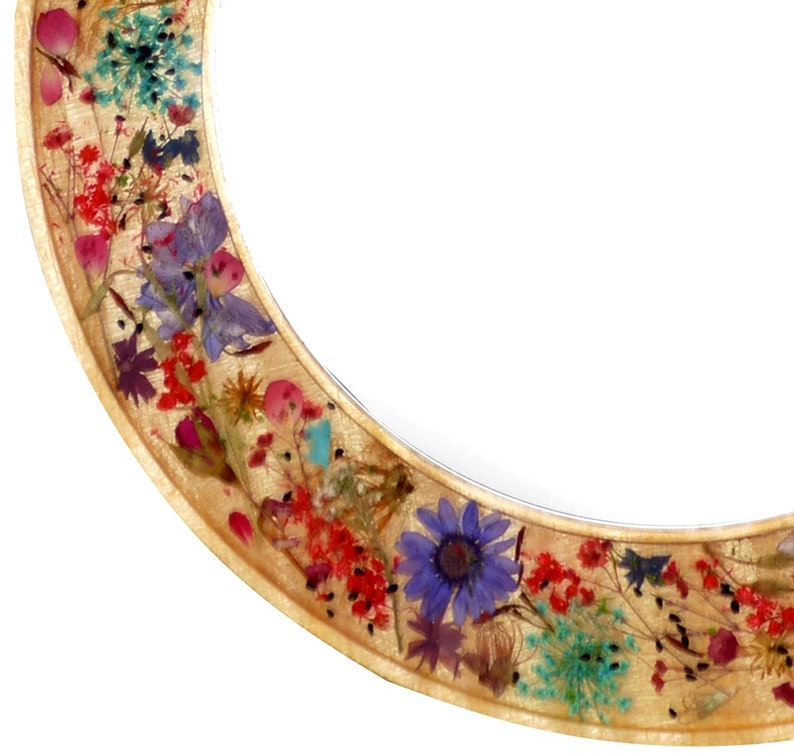 May include: A round wooden frame with a gold finish, decorated with pressed flowers and leaves in shades of red, pink, blue, green, and yellow.