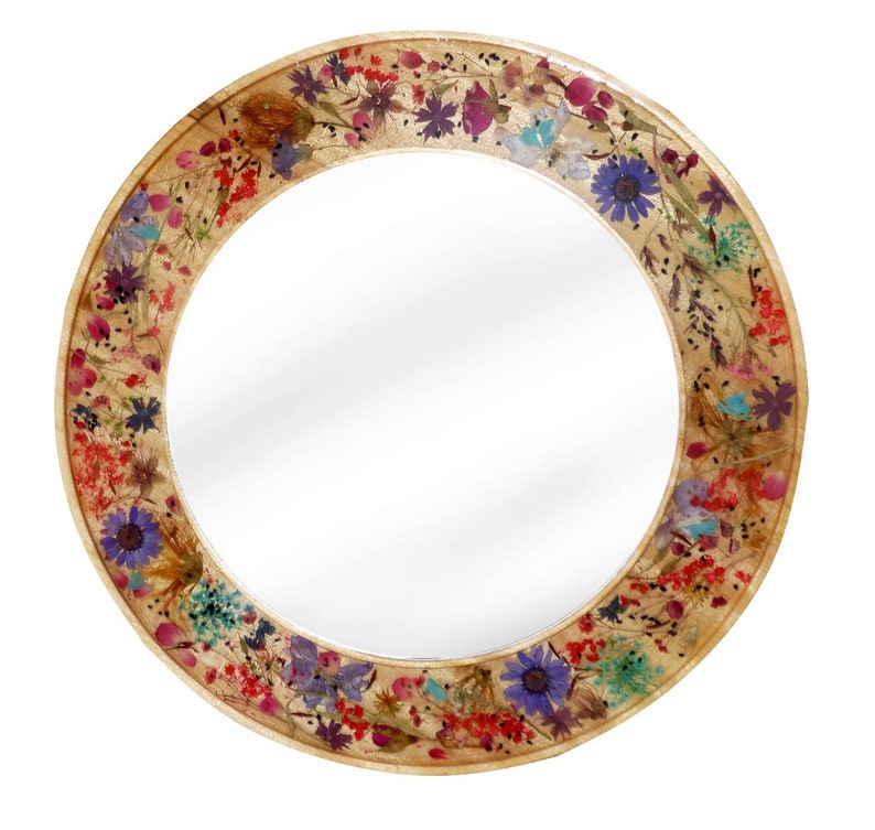 May include: Round mirror with a decorative frame made of pressed flowers. The frame features a variety of dried flowers in shades of pink, purple, blue, yellow, and red.