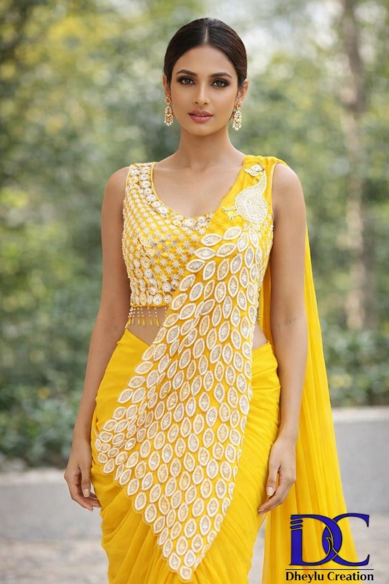 May include: A bright yellow sleeveless blouse and matching saree featuring intricate white embroidery in a repeating leaf pattern. The bodice displays dense floral stitching, while the drape showcases a prominent peacock-inspired motif.