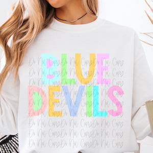 May include: A white crewneck sweatshirt featuring the text "BLUE DEVILS" printed in large, blocky letters. Each letter is filled with a different pastel color, including light blue, lime green, soft yellow, and light pink, creating a vibrant look.