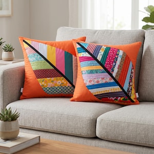 May include: Two orange leaf-shaped throw pillows with a black diagonal line. The leaves are made of colorful fabric strips. The pillows are on a gray sofa. The pillows add a decorative touch to any living space.