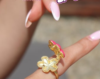 May include: A gold-toned metal ring featuring a hinged, flower-shaped locket with a bright pink enamel top. The locket is open, revealing a hollow interior. Text in the image reads Reorah COLLECTION x Totally Spies! and © 2026 Zodiak Kids & Family.