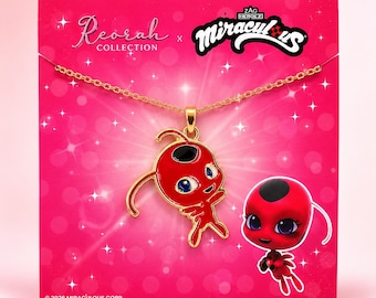 May include: A gold-tone chain necklace featuring a red and black enamel pendant of the character Tikki from Miraculous. The pendant is displayed on a bright pink backing card with the Reorah Collection and Miraculous logos and 2026 Miraculous Corp text.