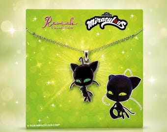 May include: A silver-toned metal necklace featuring a black enamel pendant shaped like a stylized cat-like creature with bright green eyes. The pendant is displayed on a green card with the text Reorah Collection and Miraculous.