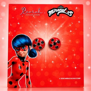 May include: A pair of round, red earrings with black spots, inspired by the Miraculous Ladybug character. The earrings are displayed on a red branded backing card featuring the Reorah Collection and Miraculous logos, along with the text 2026 MIRACULOUS CORP.