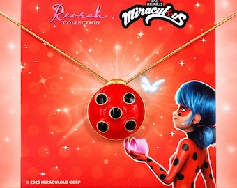 May include: A gold-toned chain necklace featuring a round, red pendant with five black spots, resembling a ladybug. The pendant is displayed on a red card with the text Reorah Collection and Miraculous, featuring an illustration of a character.
