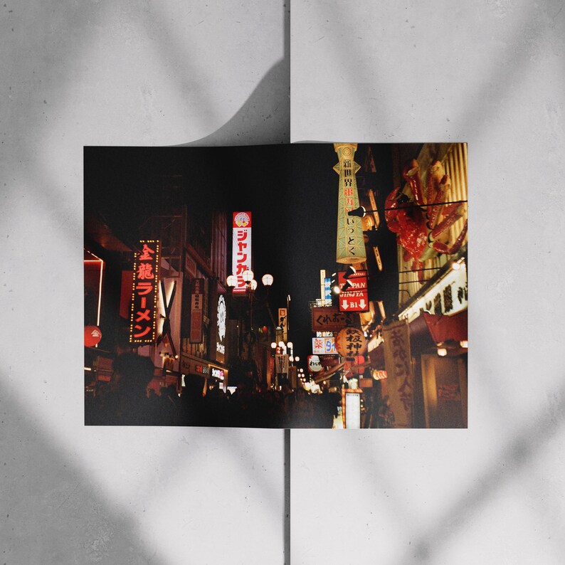 May include: A photograph of a Japanese street at night, filled with neon signs in red, white, and yellow. The signs display Japanese characters. The image has a warm, vintage aesthetic, with a focus on the illuminated signs.