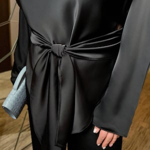Detail of satin women pantsuit showing adjustable tie belt and smooth silk look fabric