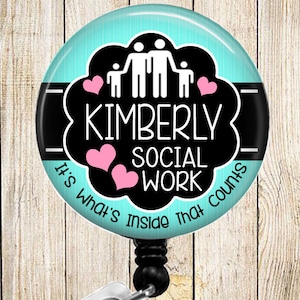 May include: A turquoise blue badge reel with a black and white design. The design features a family of four stick figures with hearts and the text "Kimberly Social Work It's What's Inside That Counts".