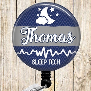 May include: A blue and gray round badge holder with a white chevron pattern, a white moon and stars, and the text "Thomas SLEEP TECH".