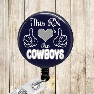 May include: A blue and white retractable badge holder with a round button that says "This RN's the Cowboys" with a thumbs up and heart graphic.